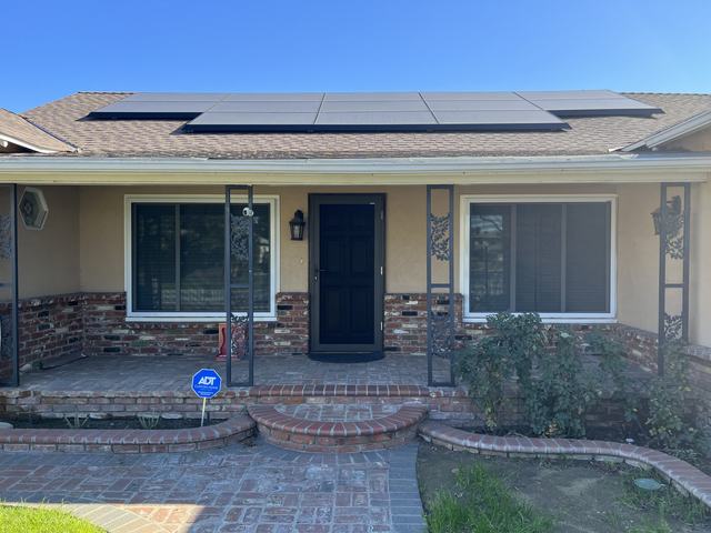 Ranch home with solar panels, a black hinged security screen door and security screens on two wide front windows