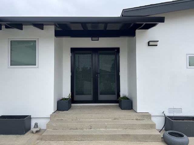 Black double security screen doors on the front entry of a modern white home