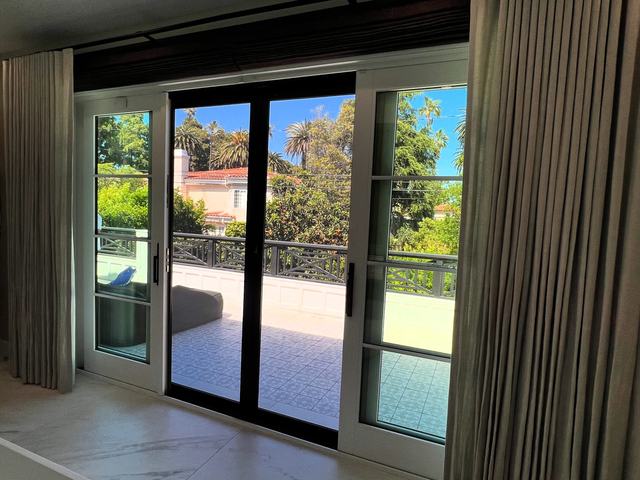 View from inside through black sliding security screens on French sliders to a balcony and palm trees