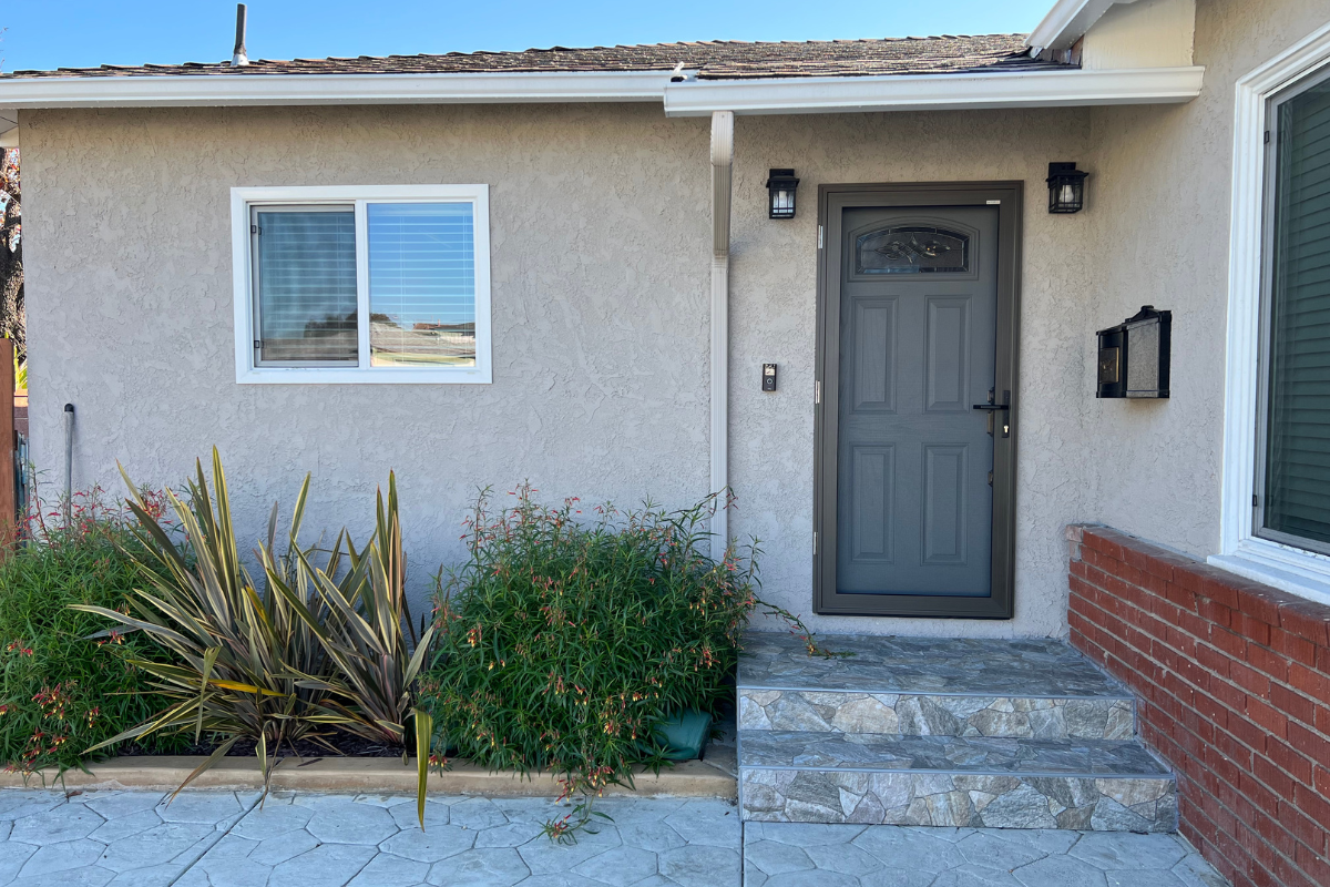 The front view of a dark gray security screen door mounted over a main entry door in Southern California.